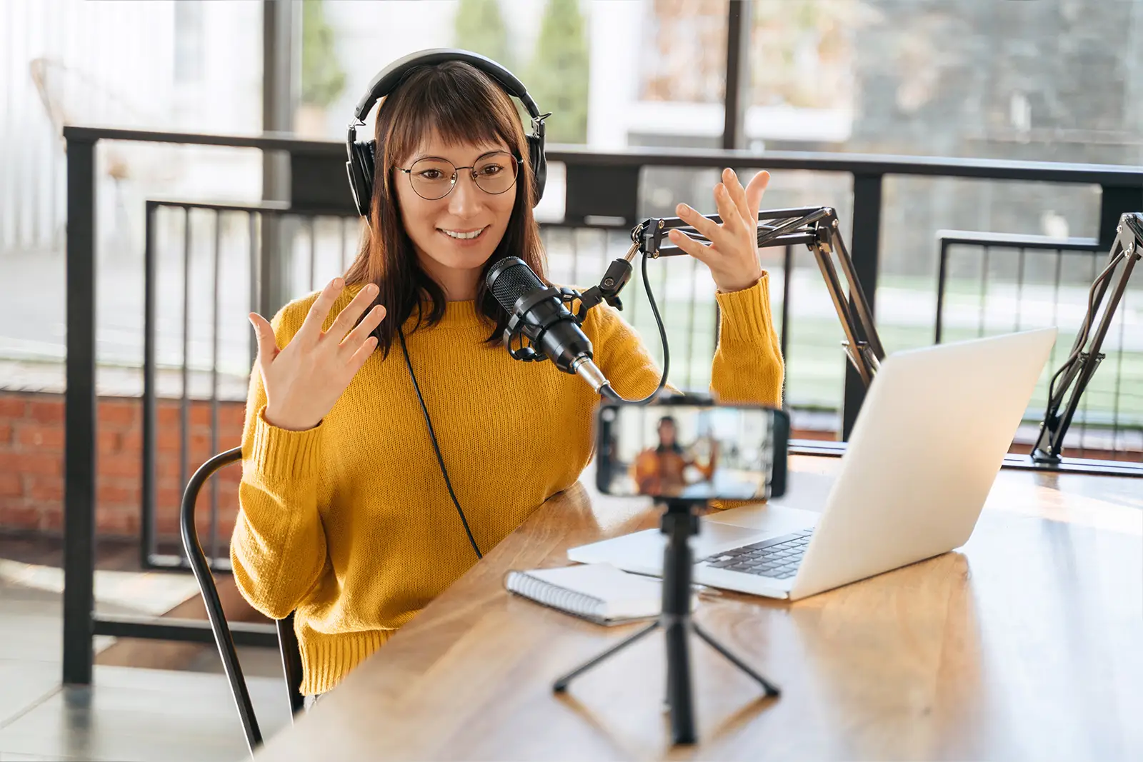 Eine Frau arbeitet an einem Podcast mit Mikrofon und Kopfhörer